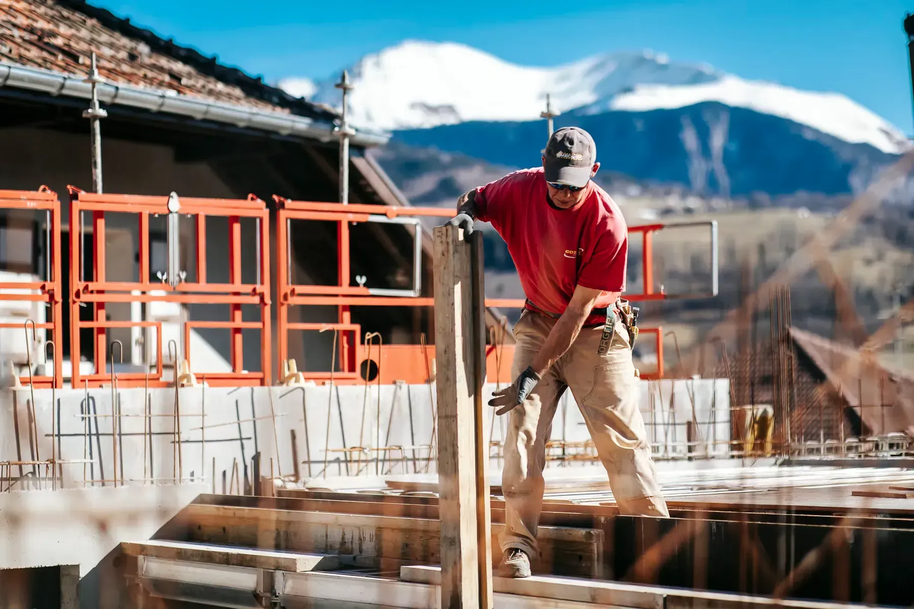 Membre de l'équipe Grange Gaël sur un chantier de montagne, sommets enneigés en fond
