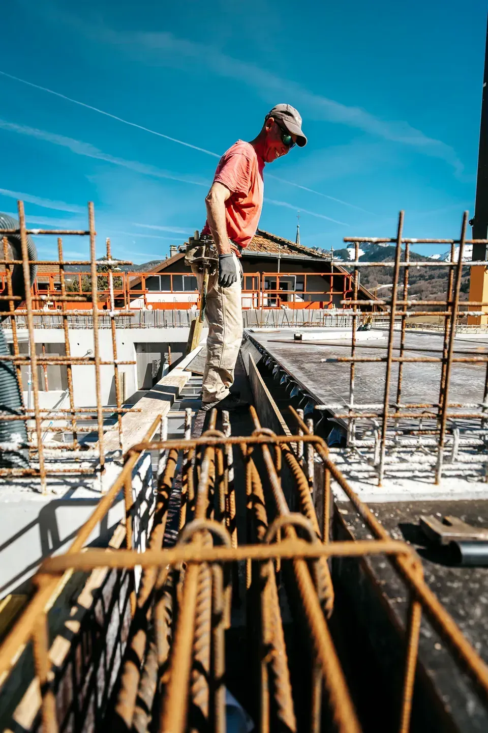 Maçon debout sur les armatures d'un plancher en cours de ferraillage