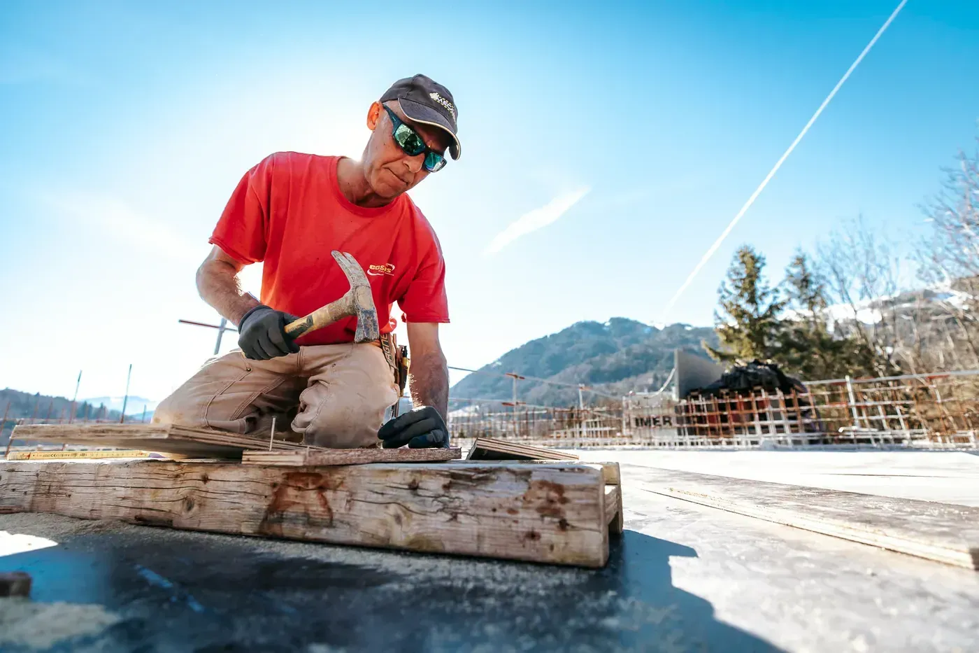 Maçon découpant une planche de coffrage sur un chantier ensoleillé