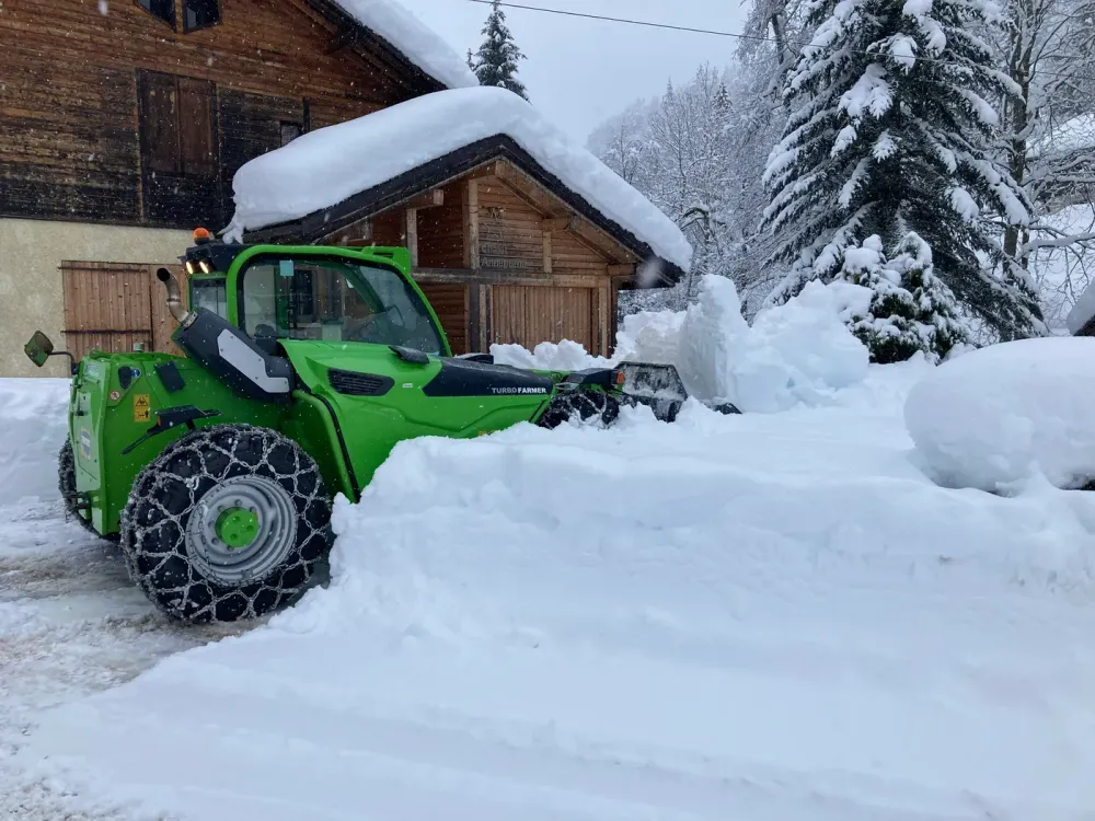 Chargeuse télescopique en intervention devant un chalet sous la neige