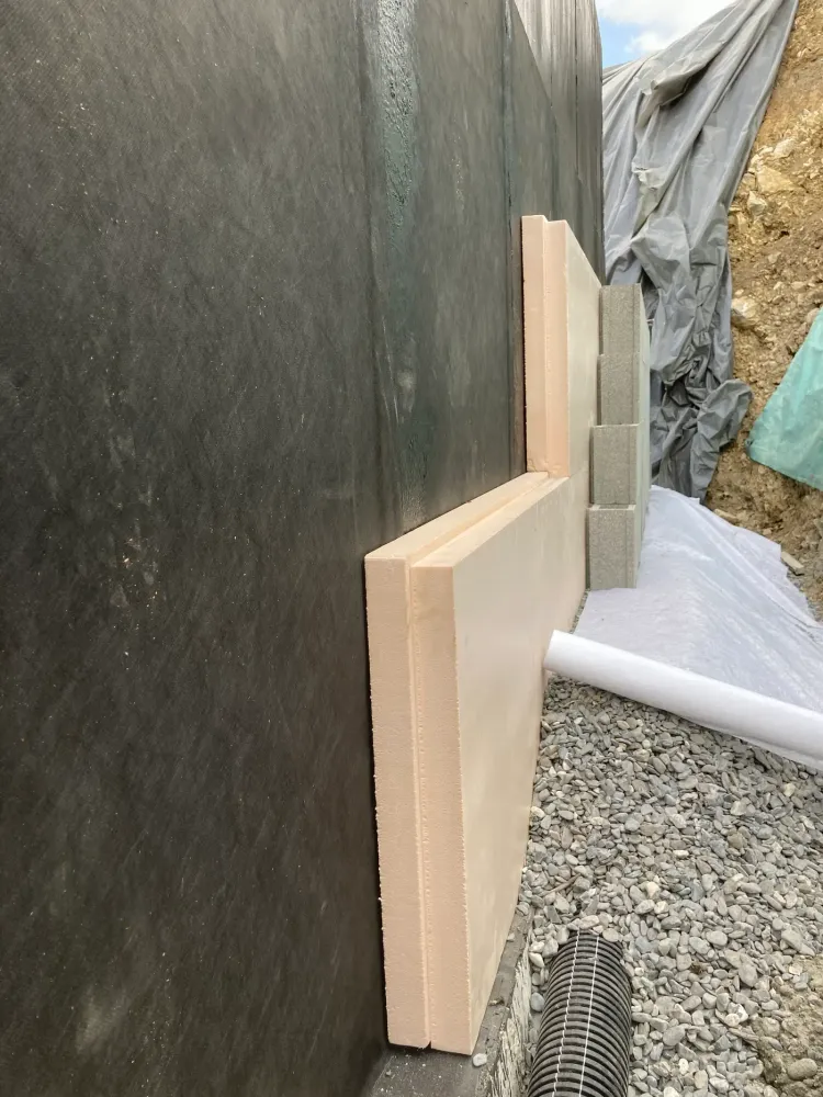 Isolant et blocs de drainage posés contre l'étanchéité d'un mur enterré, drain au pied de la fouille